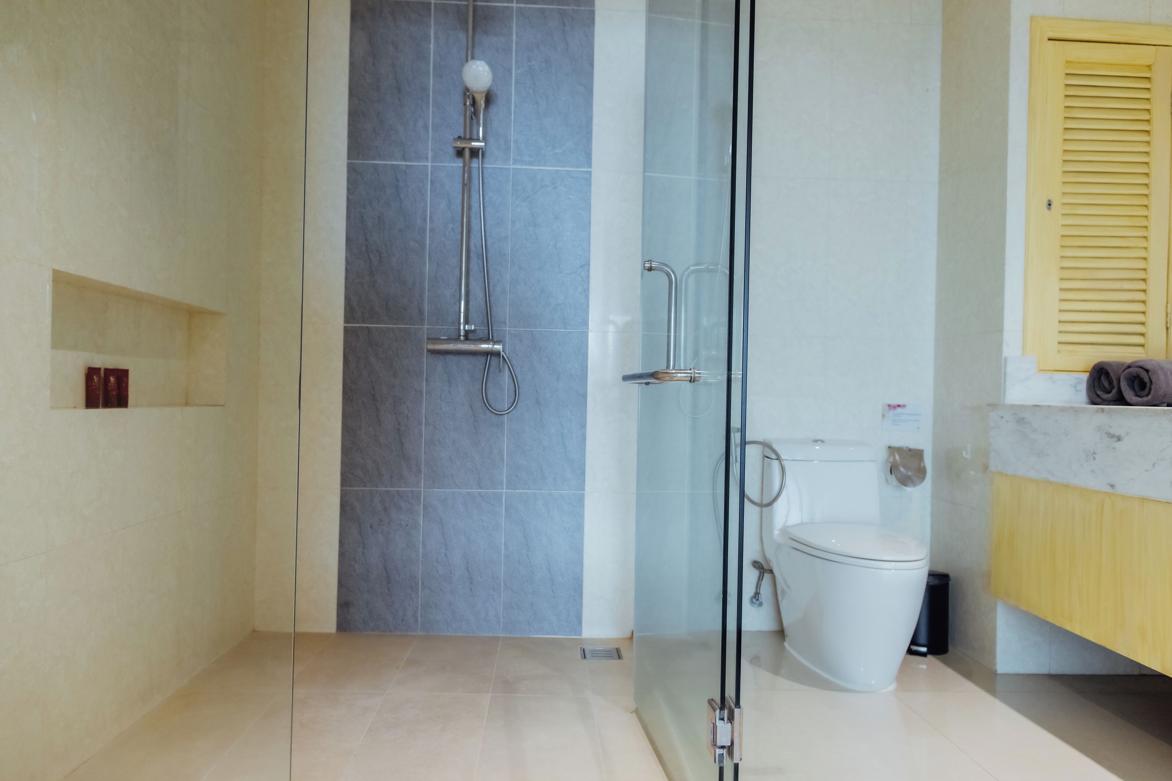 A modern bathroom with a glass-enclosed shower, a toilet, and a marble countertop.