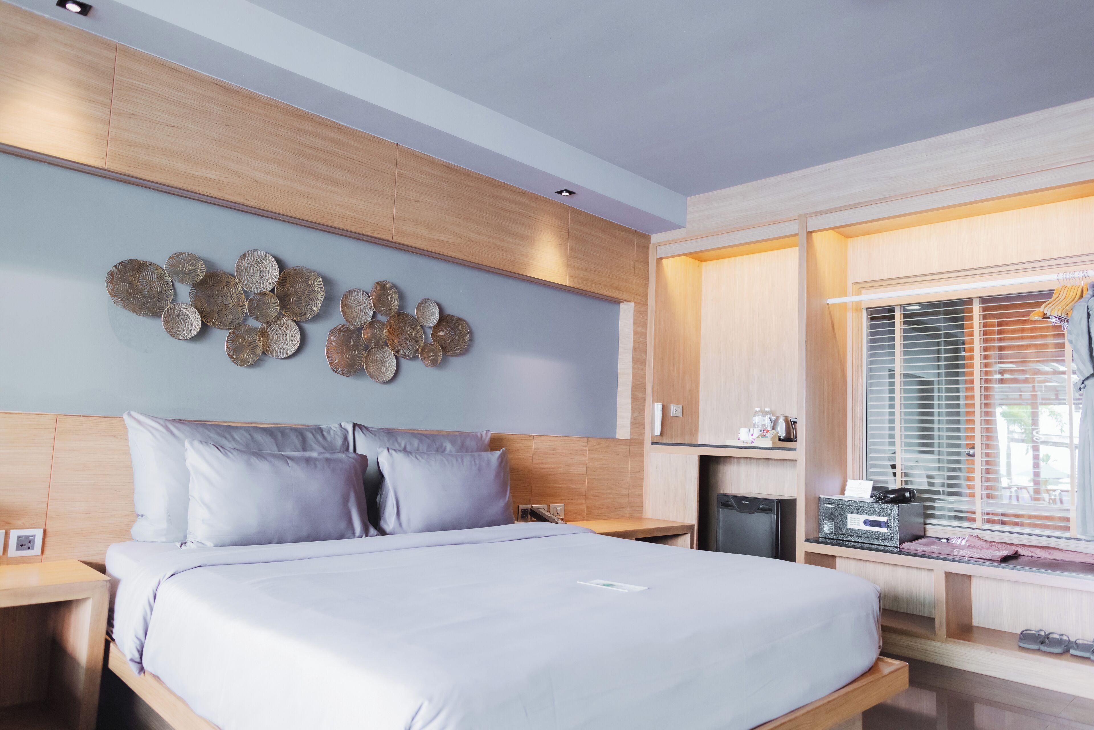 A modern bedroom with a large bed, wooden headboard, and a wall-mounted decorative piece.