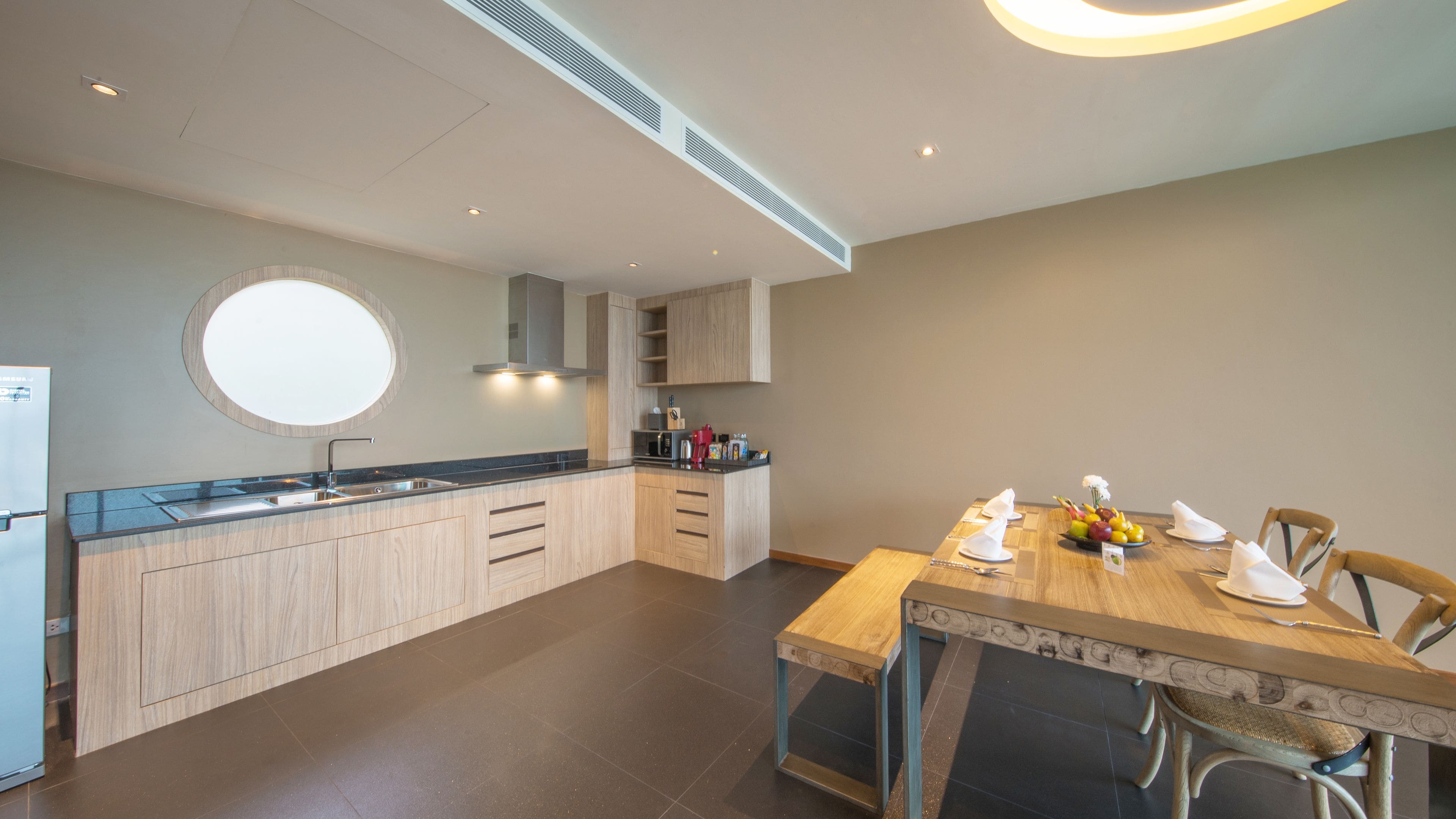 Una cocina moderna con una isla central, armarios empotrados y un comedor con mesa y sillas de madera.