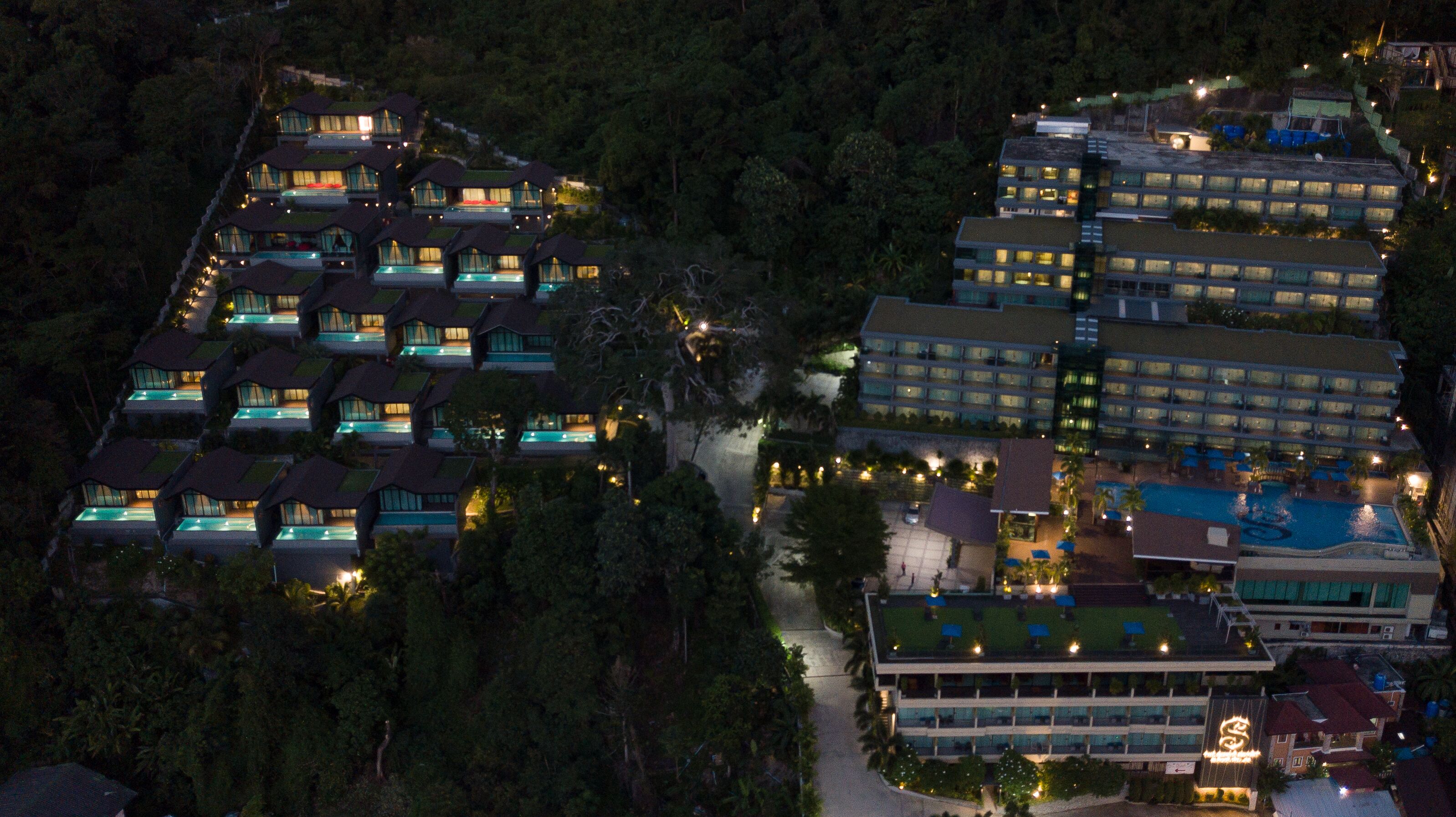 A resort with multiple buildings, including a pool area and a large building with a distinctive sign.