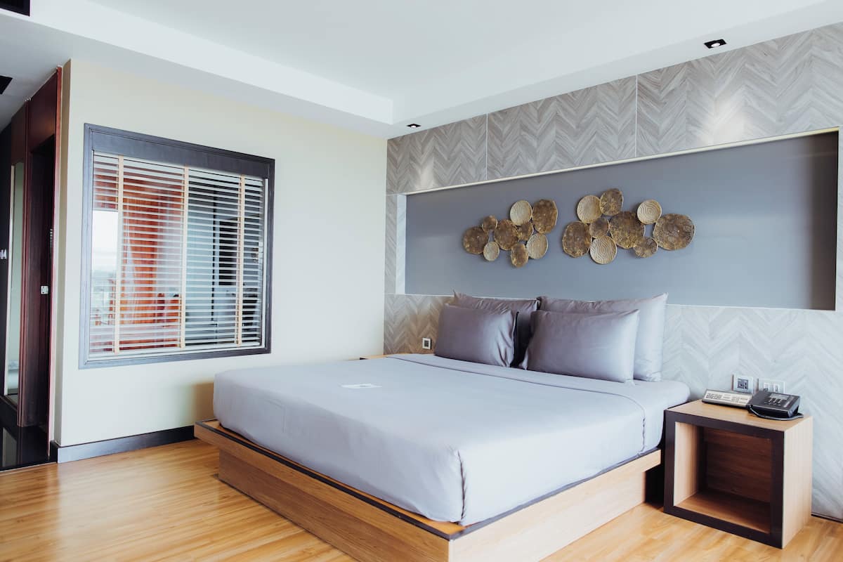 A modern bedroom with a bed, a bedside table with a phone, and a decorative wall piece.