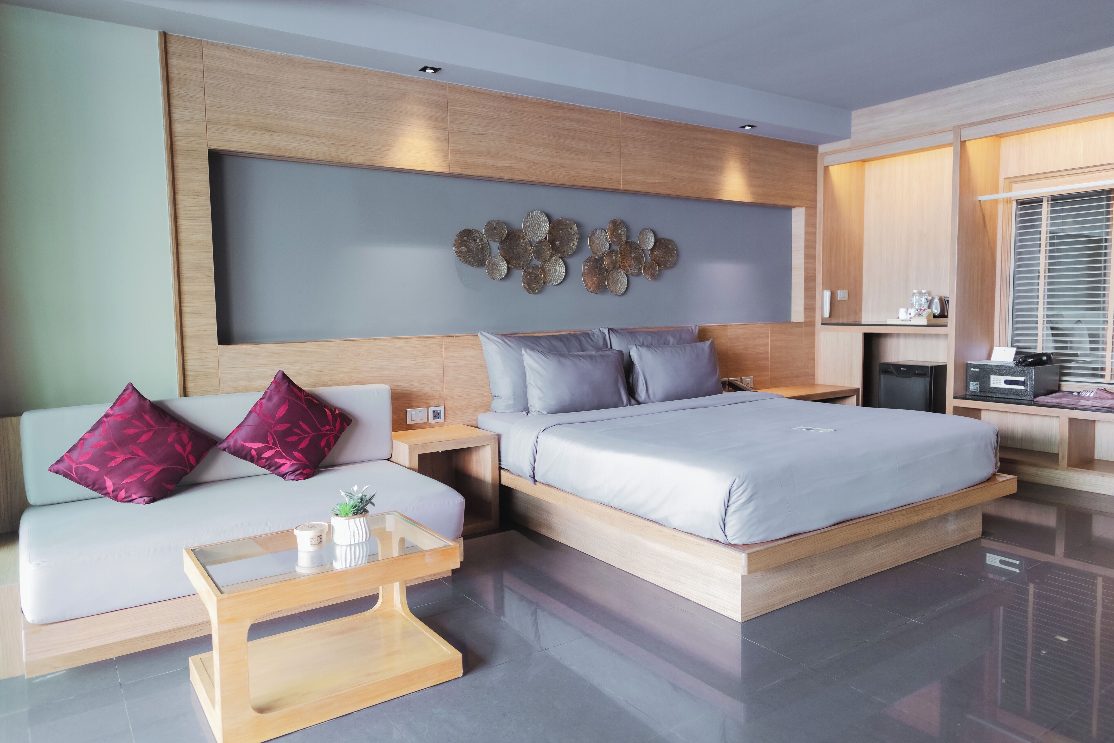 A modern bedroom with a bed, a sofa, a coffee table, and a wall-mounted artwork.