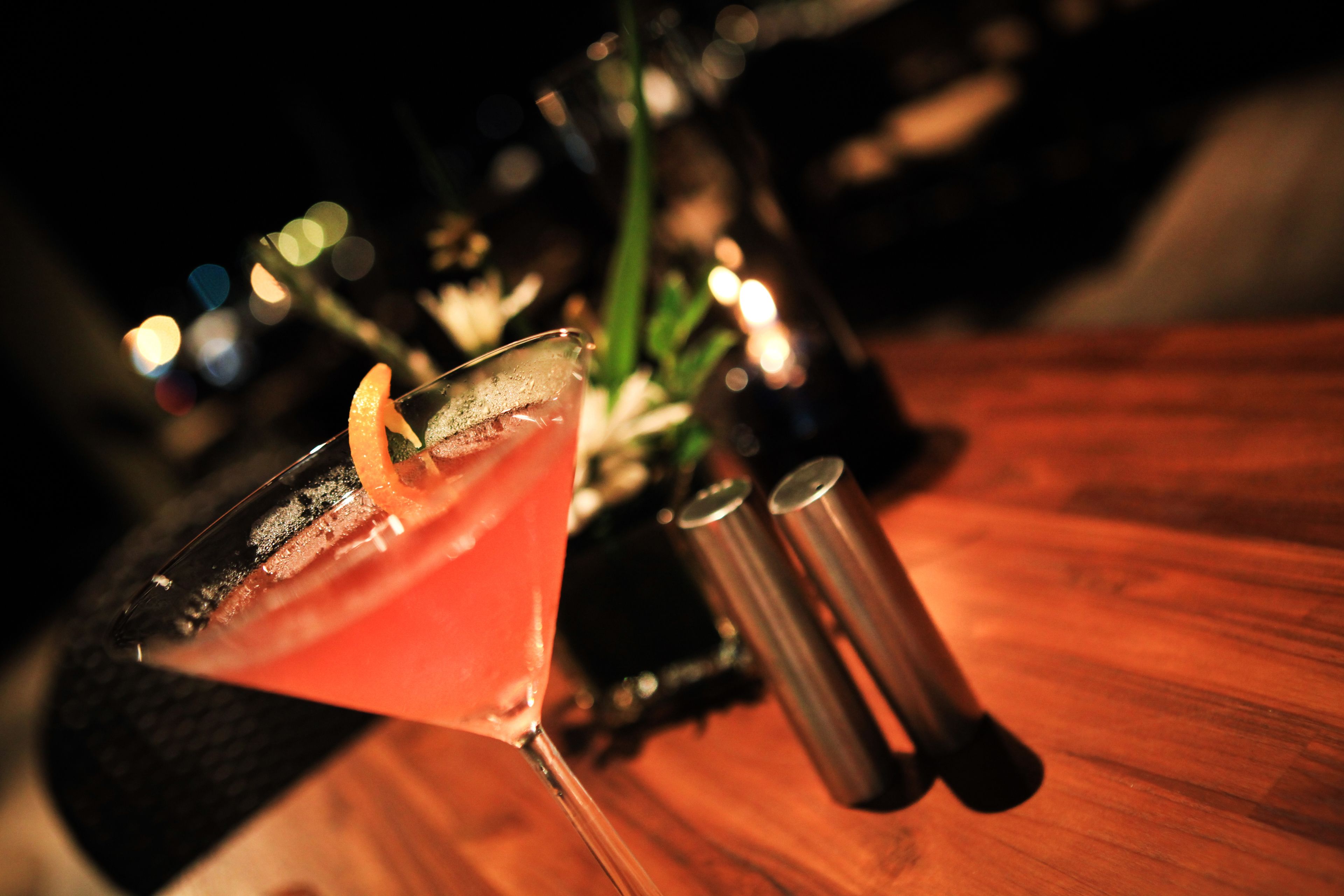 A martini glass with a garnish on a wooden bar counter.