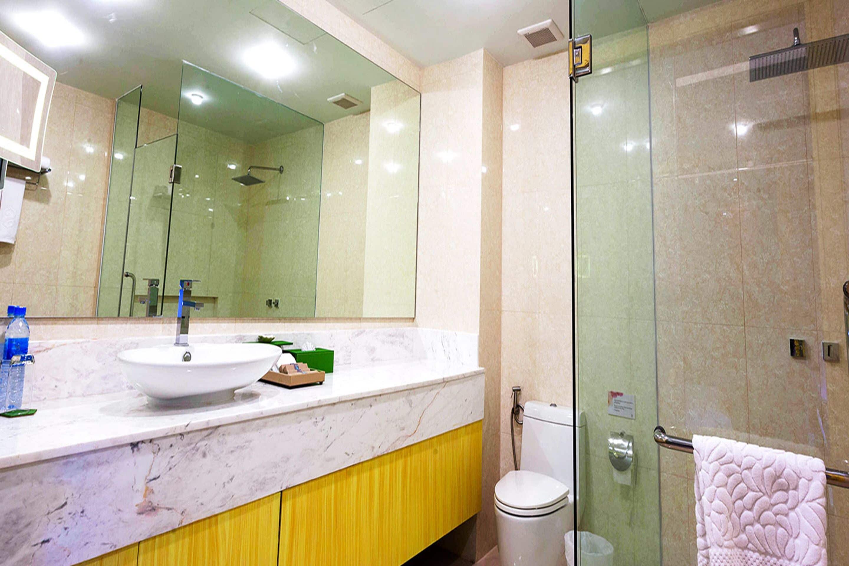 A modern bathroom with a glass-enclosed shower, a white sink, and a yellow cabinet.
