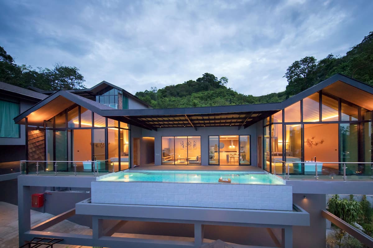 A modern house with a swimming pool, large glass windows, and a covered patio area.