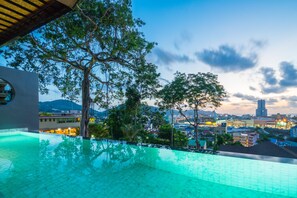 An infinity pool with a view of a cityscape at dusk. - The Senses Resort & Pool Villas, Phuket (Patong)