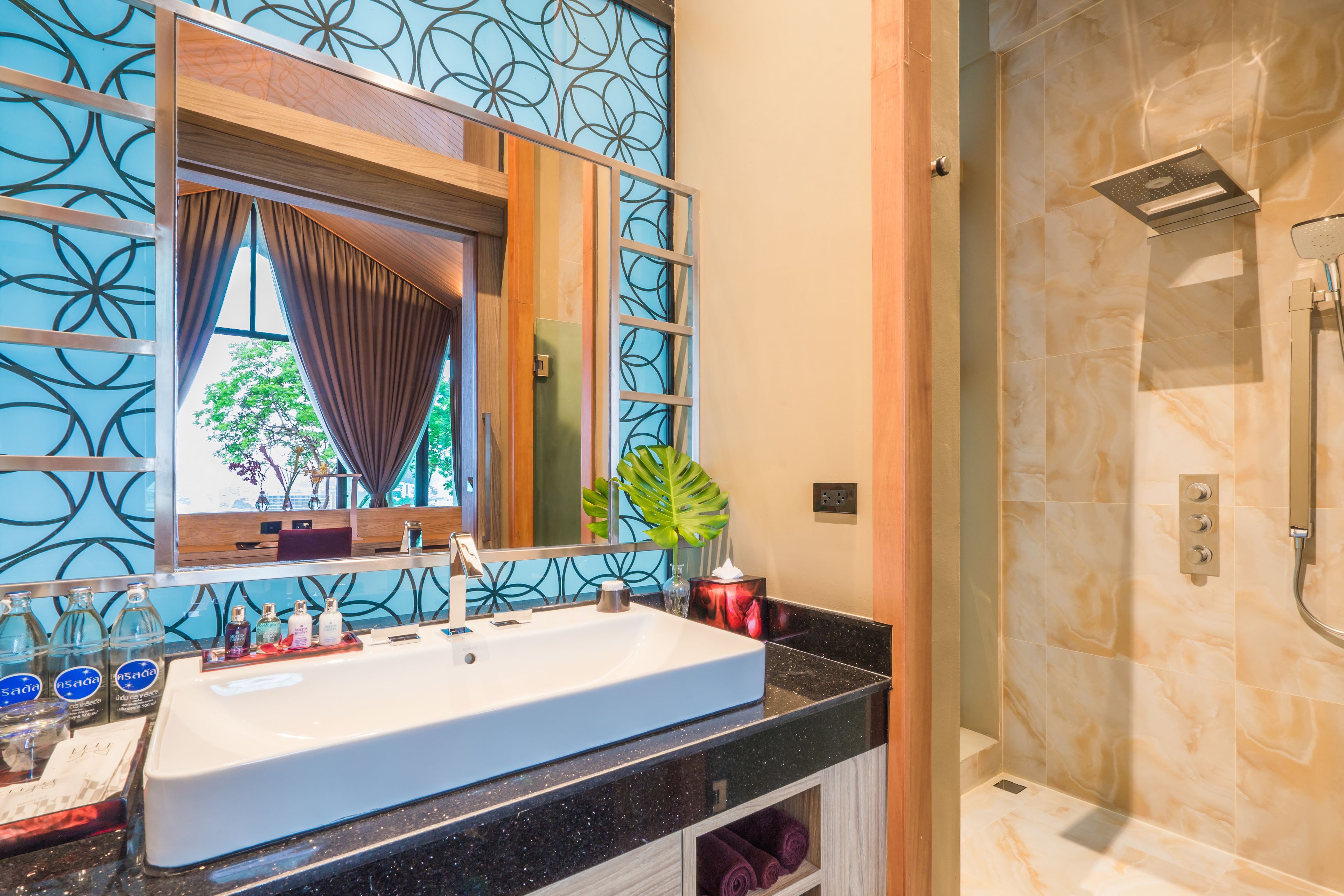 A bathroom with a large mirror, a sink, and a shower.