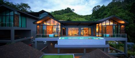 A modern house with a swimming pool, large glass windows, and a balcony.