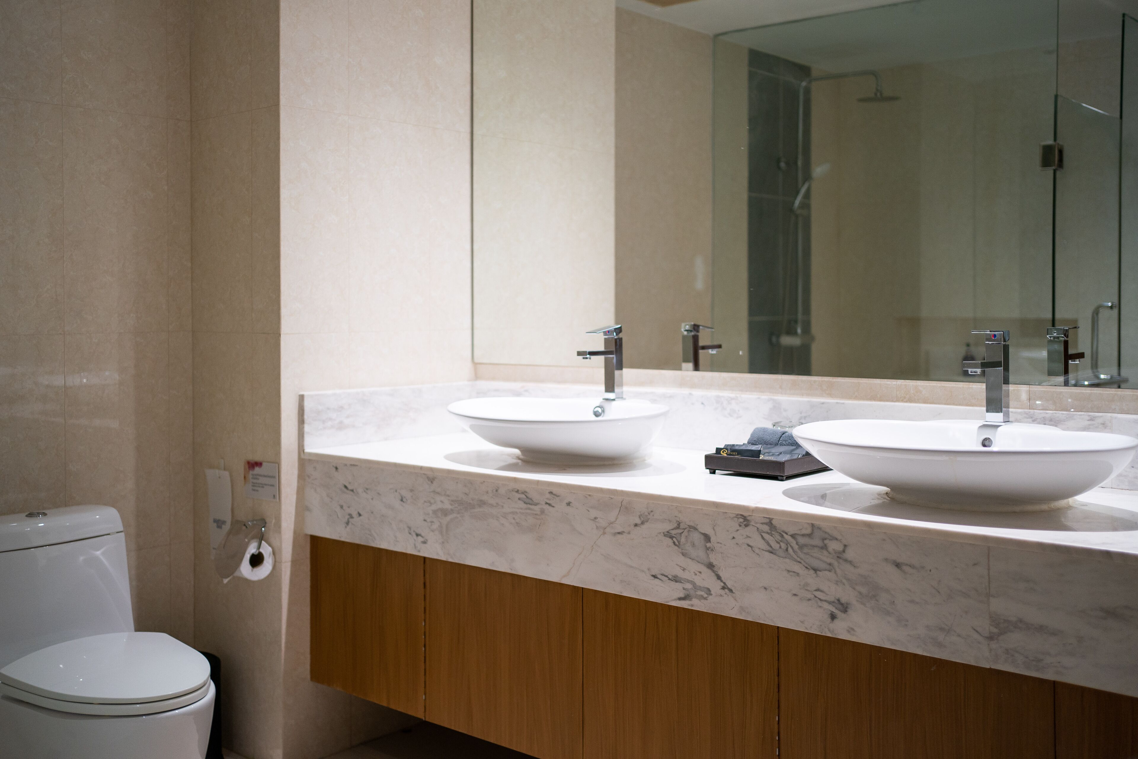Un baño moderno con dos lavamanos, un inodoro y un espejo grande.
