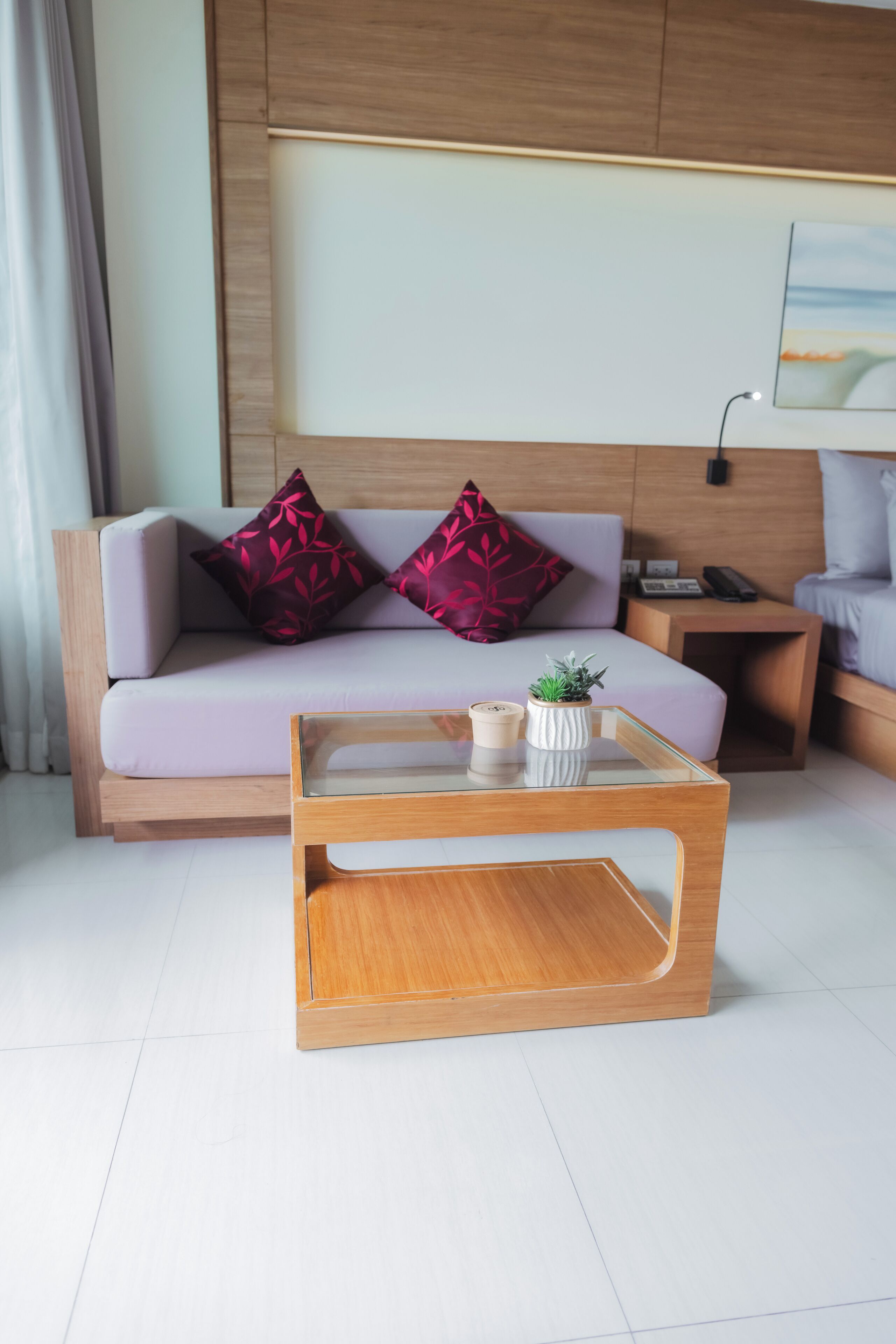 Een moderne woonkamer met een bank, twee decoratieve kussens, een glazen salontafel en een kleine plant.