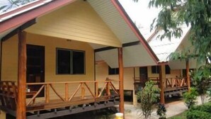 A row of wooden cabins with a porch, a window, and a small garden area. - Baan Tai Rom Yen Resort (Surat Thani)