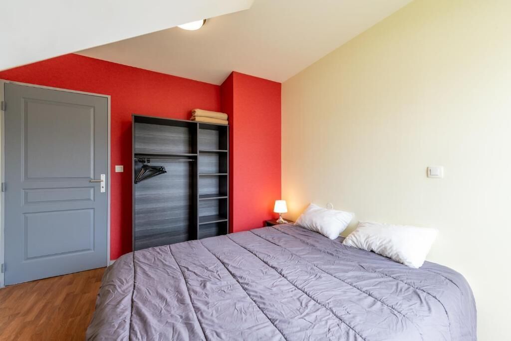 Une chambre à coucher avec un lit, une armoire, une porte et une table de chevet avec une lampe.