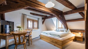 A bedroom with a wooden ceiling, a bed, a desk, and a chair.