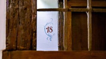 A room number 18 on a white paper with a decorative border, partially visible through a wooden window frame.