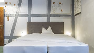 A double bed with a headboard, a green carpet, and a ceiling with exposed beams.