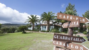 Un panneau indicateur indiquant les directions vers le « CAFÉ-BAR », la « PISCINE », le « PARC DE PATINOIRE », « GABALLOS » et les « TERRENS DE TENNIS ».