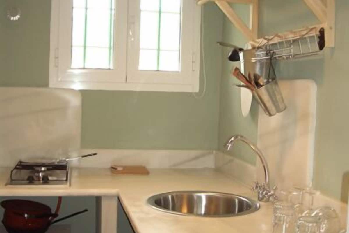 A kitchen with a sink, a stove, and a window with blinds.