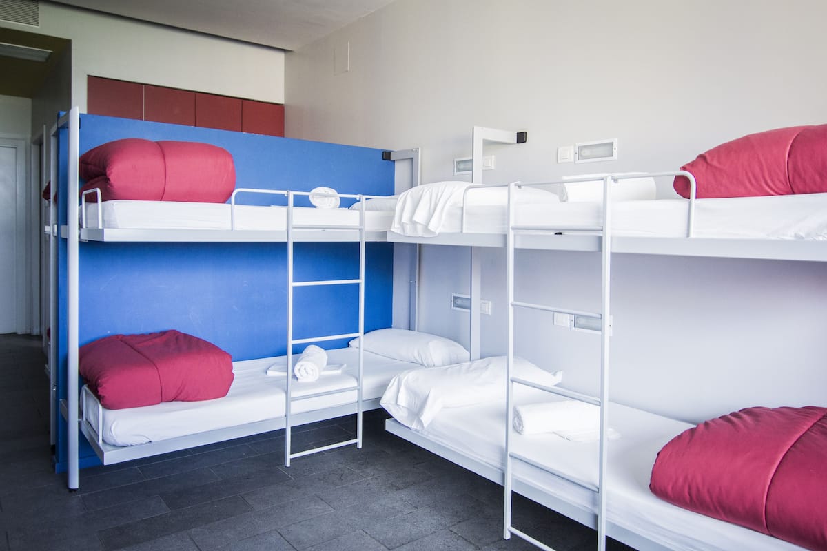 A bunk bed room with three levels, each with a mattress and pillows.