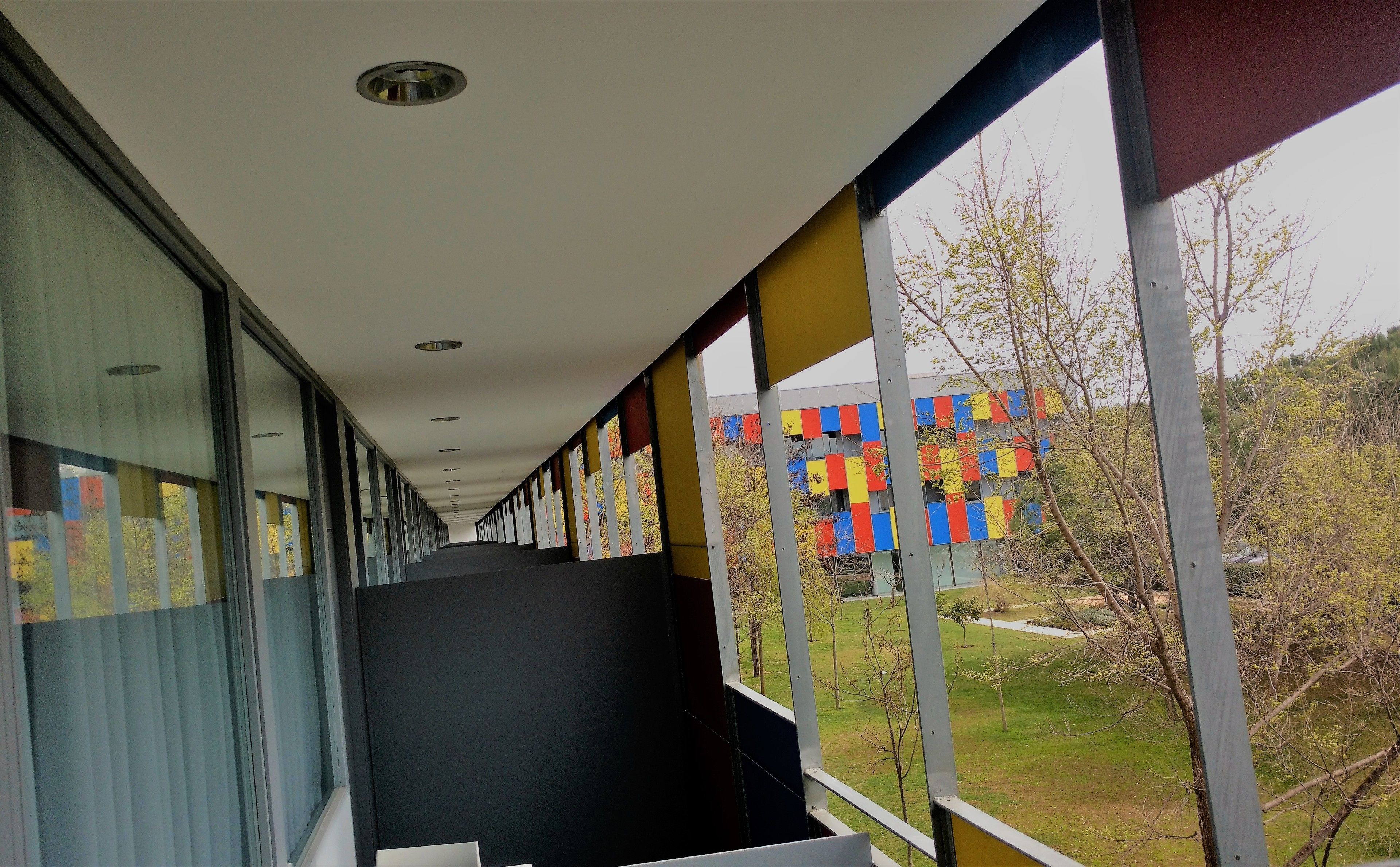 A corridor with a view of a colorful building and a grassy area.