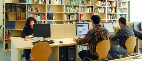 Une bibliothèque dotée de nombreux postes informatiques et de rayonnages remplis de livres.