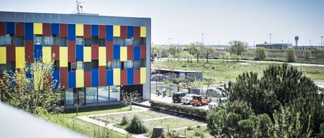 Un edificio moderno con fachada colorida, rodeado de un césped cuidado y árboles.