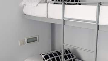 A bunk bed with two levels, each with a pillow and a control panel on the wall.