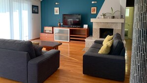 Uma sala de estar moderna com uma parede de destaque azul-esverdeada, uma televisão de tela plana, uma lareira e dois sofás.