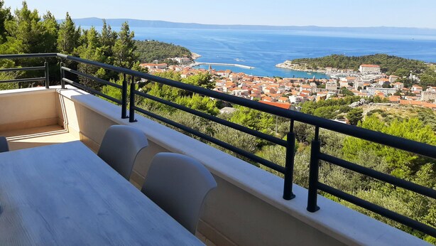 Uma varanda com vista para uma cidade costeira, incluindo edifícios e um mar azul cristalino.