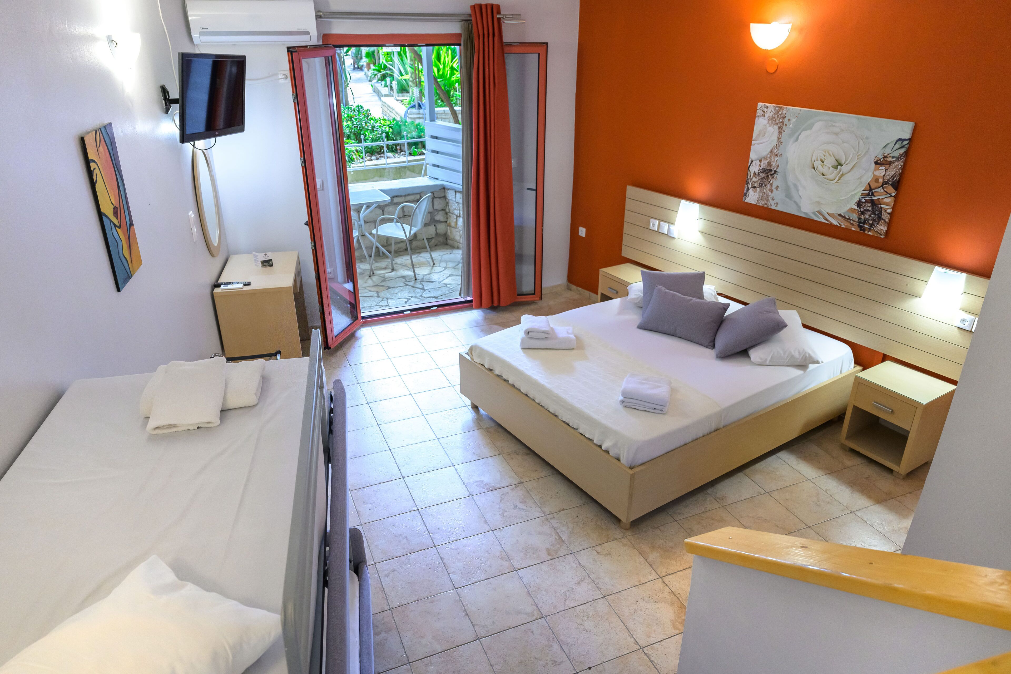 Ein Hotelzimmer mit Bett, Schreibtisch, Stuhl, Fernseher und einer Glastür zum Außenbereich.