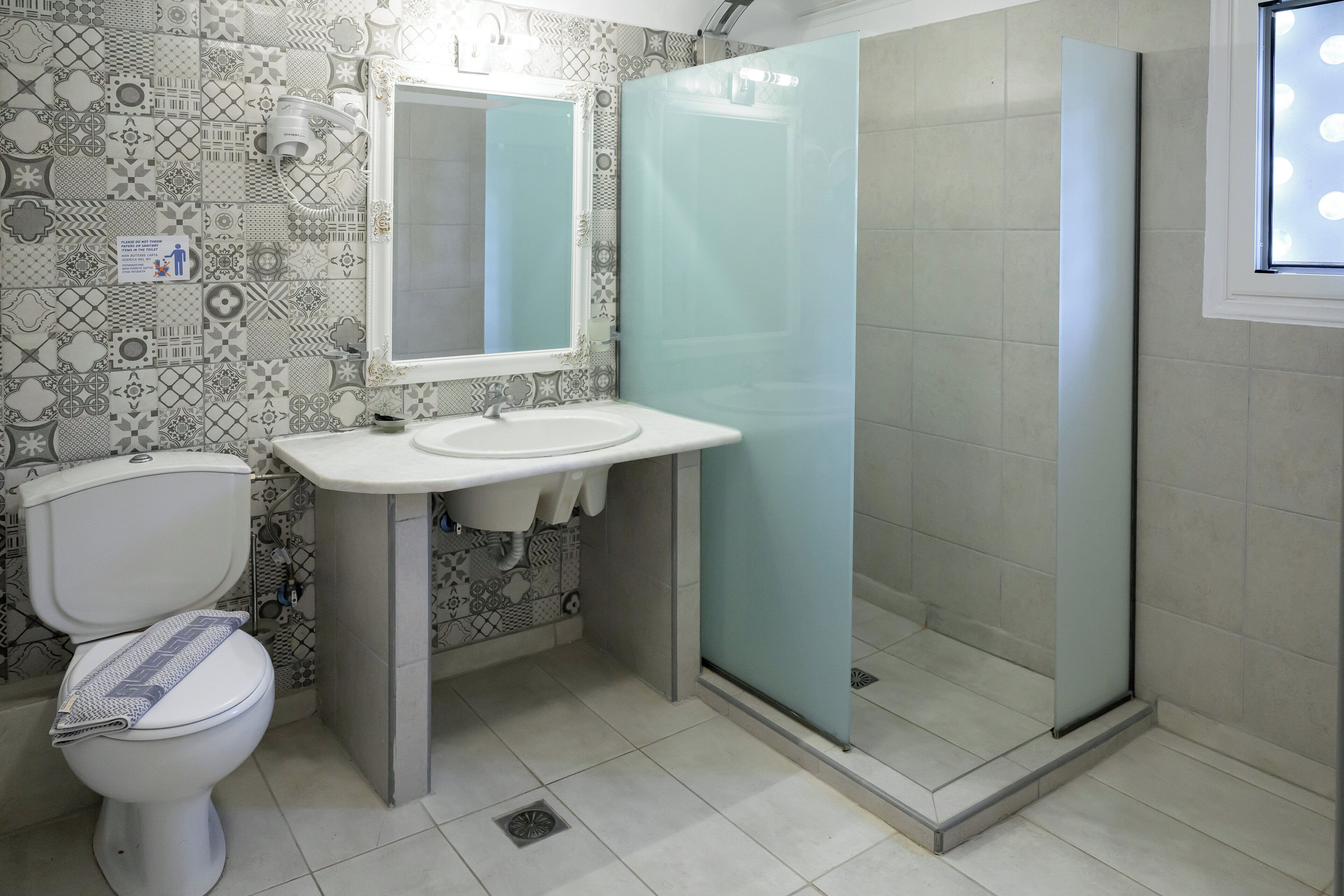 Un baño con inodoro, lavamanos y cabina de ducha de vidrio.