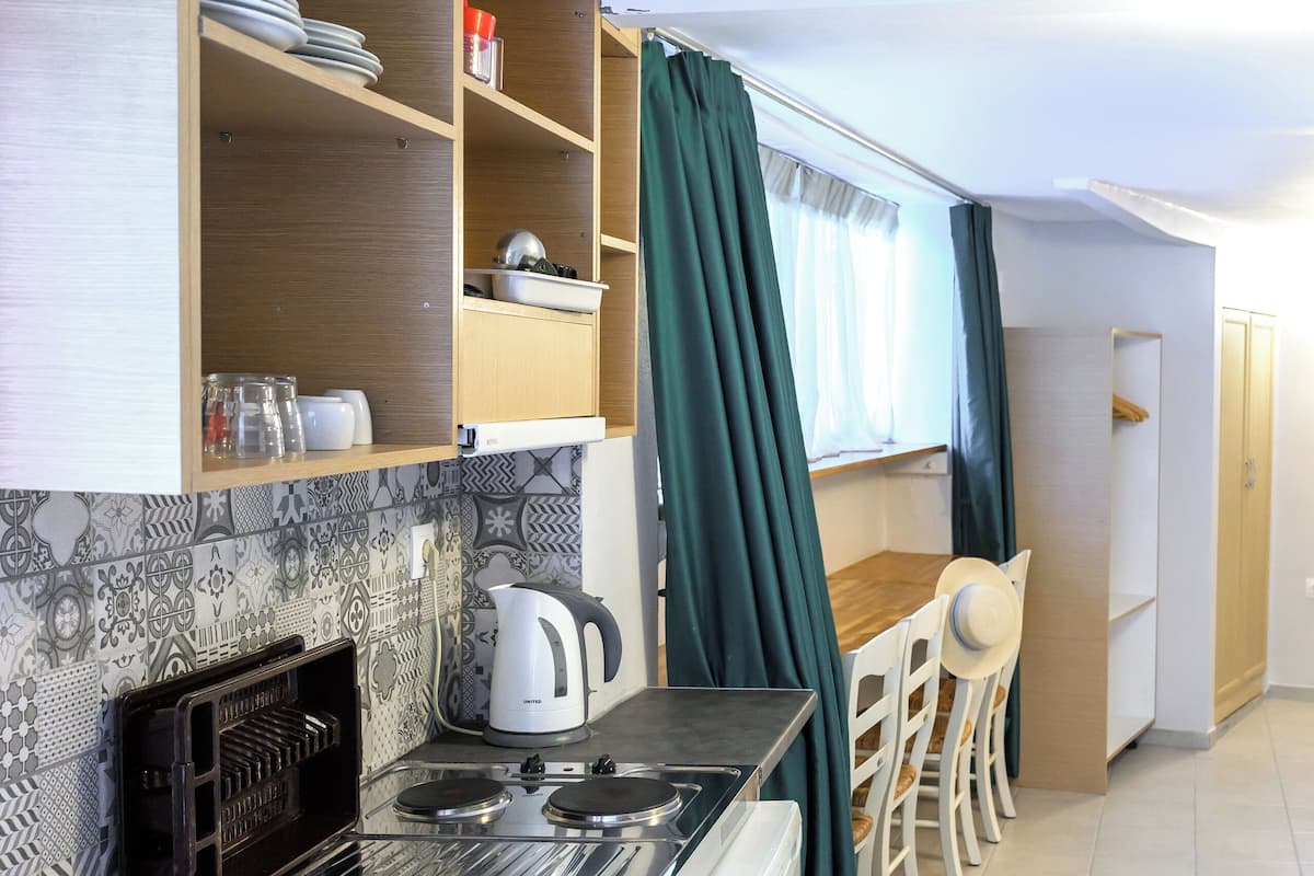 A compact kitchen with a stove, sink, and a dining area with chairs and a table.