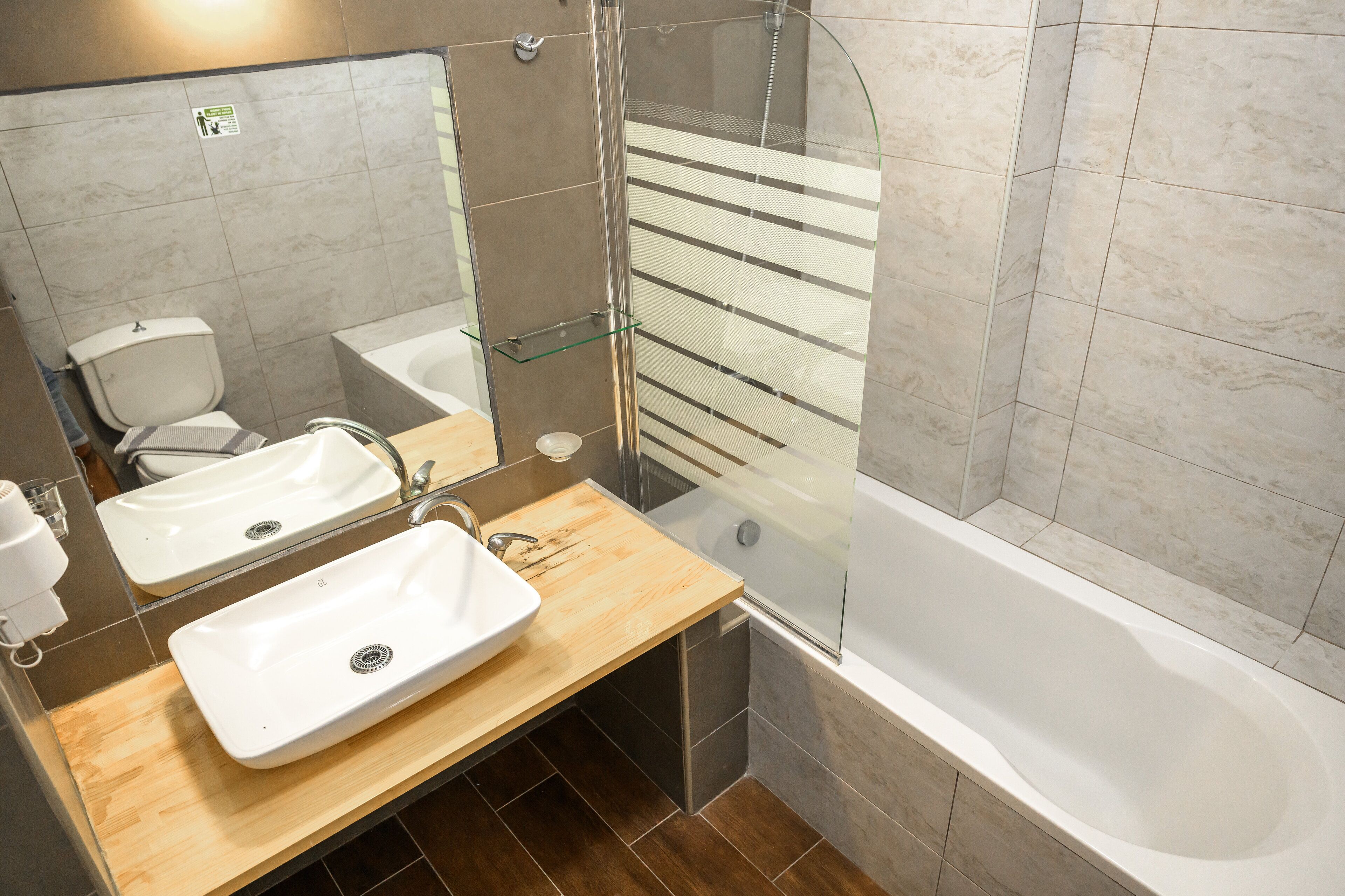A modern bathroom with a glass-enclosed shower, two sinks, and a bathtub.