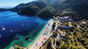 An aerial view of a coastal area with a beach, boats, and buildings.