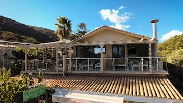 A beachside hotel with outdoor seating, a covered patio, and a sign indicating it is the Rouda Beach Hotel.