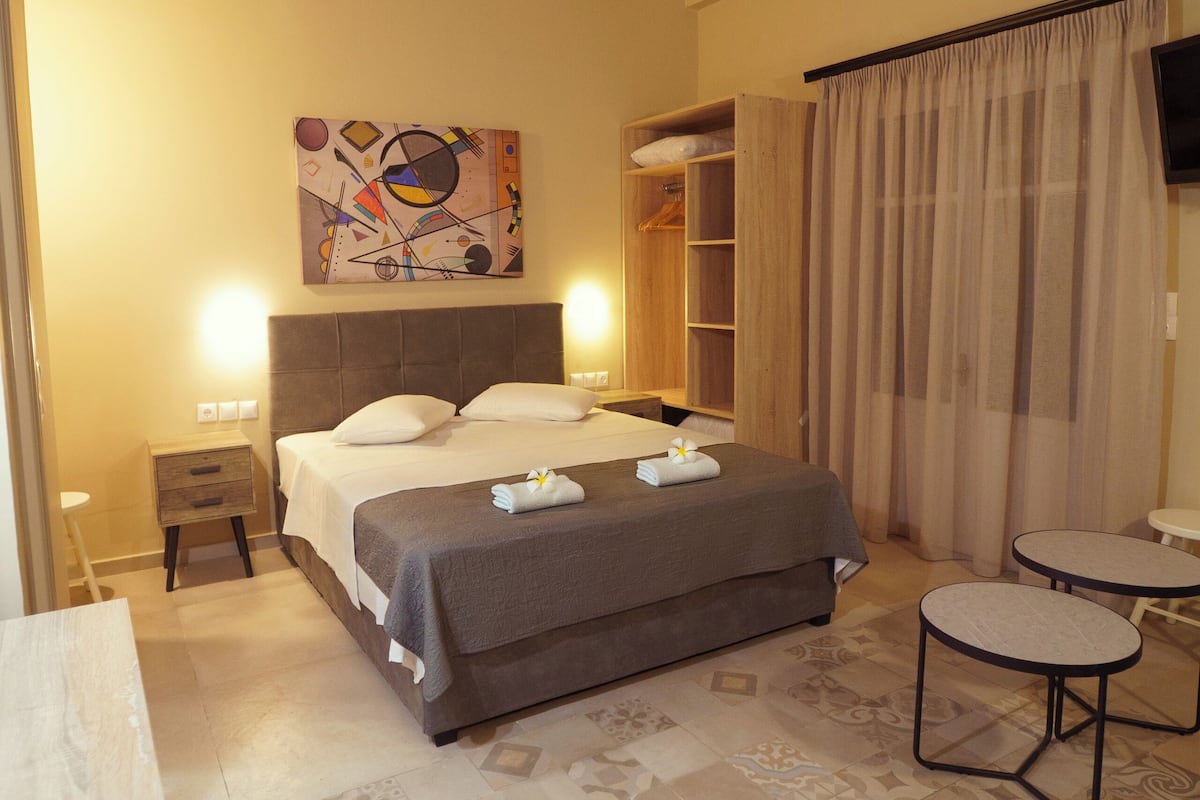 A bedroom with a bed, bedside tables, a wardrobe, a small table, and a TV.