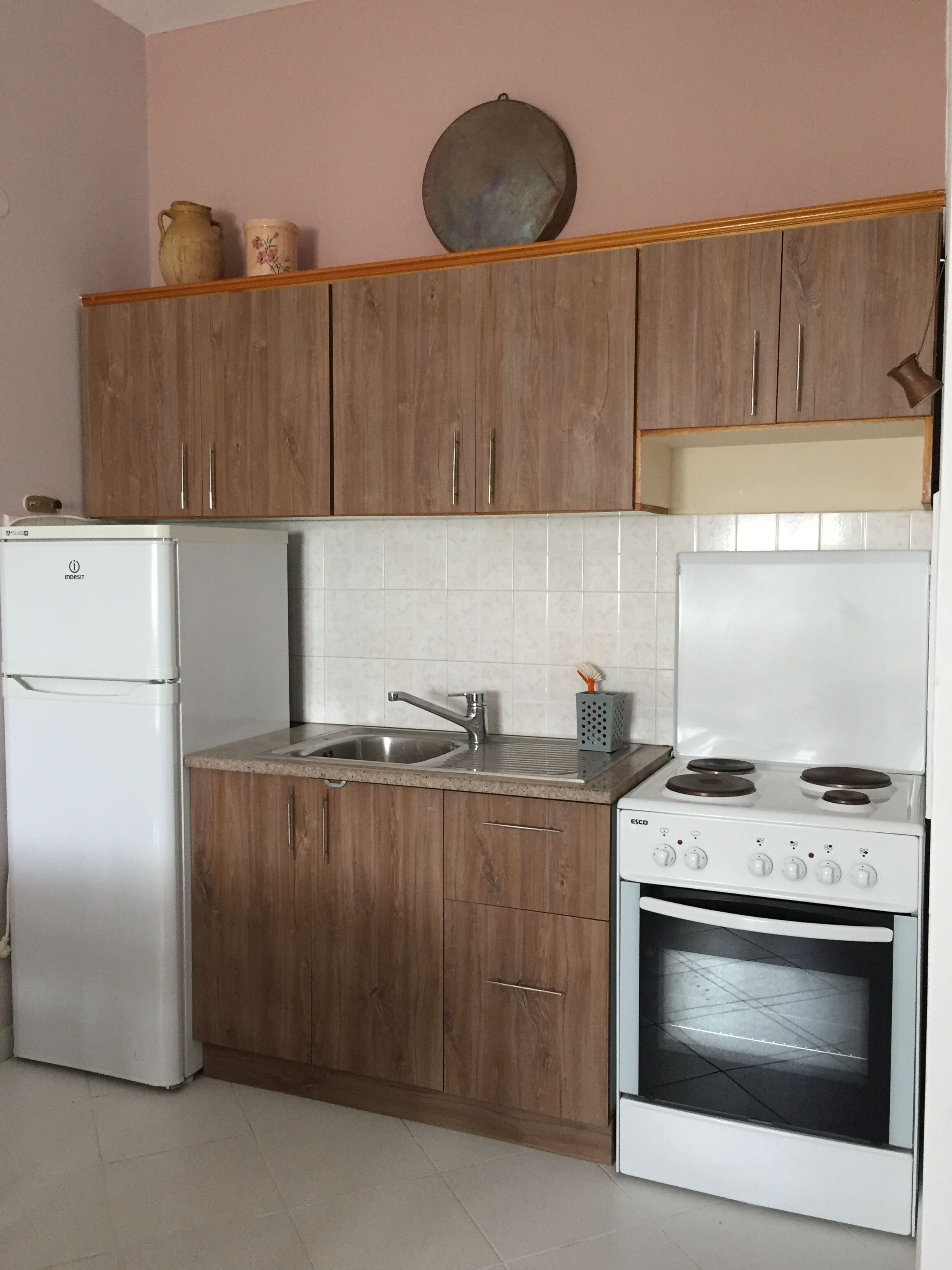 A compact kitchen with wooden cabinets, a white refrigerator, a sink, and a stove.