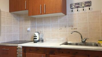 A kitchen with wooden cabinets, a stainless steel sink, a coffee maker, and a tiled backsplash.