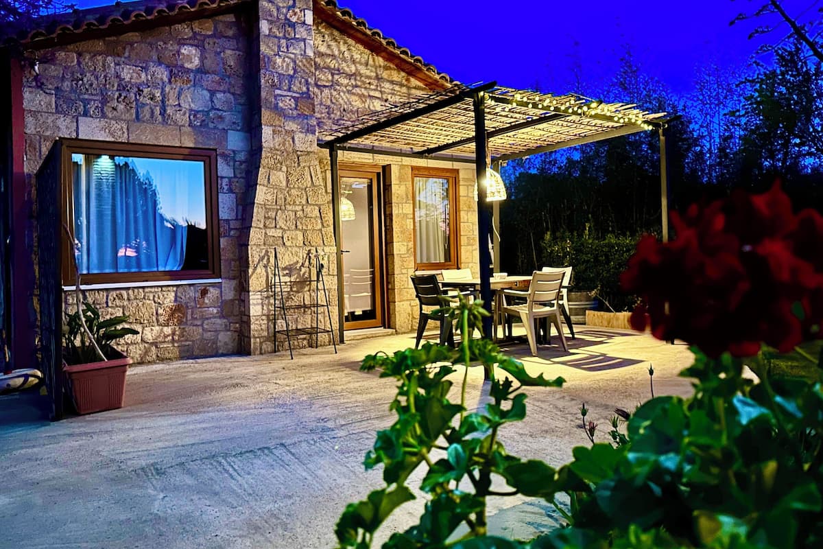 A stone building with a patio area featuring outdoor seating and a pergola.