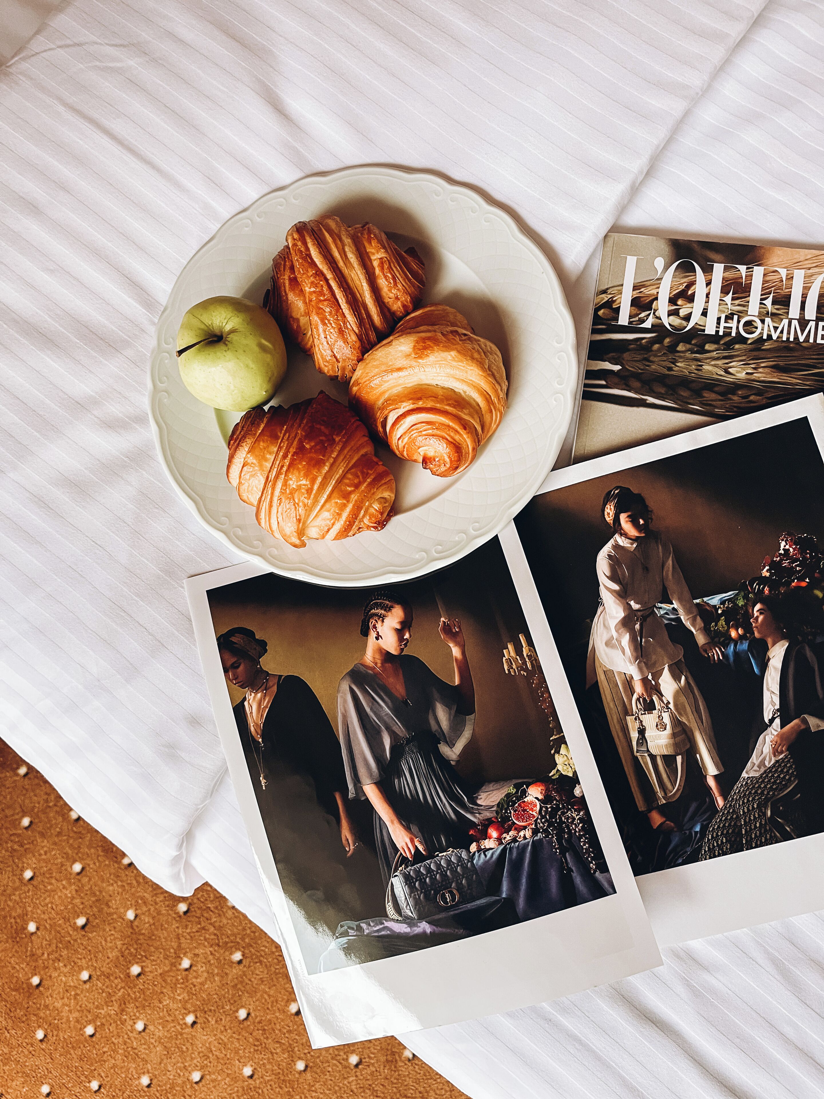 Una mesa con croissants, una manzana y una revista.