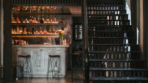 A bar area with shelves of bottles, stools, and a staircase. - Aleksandrovskiy Hotel (Odesa)