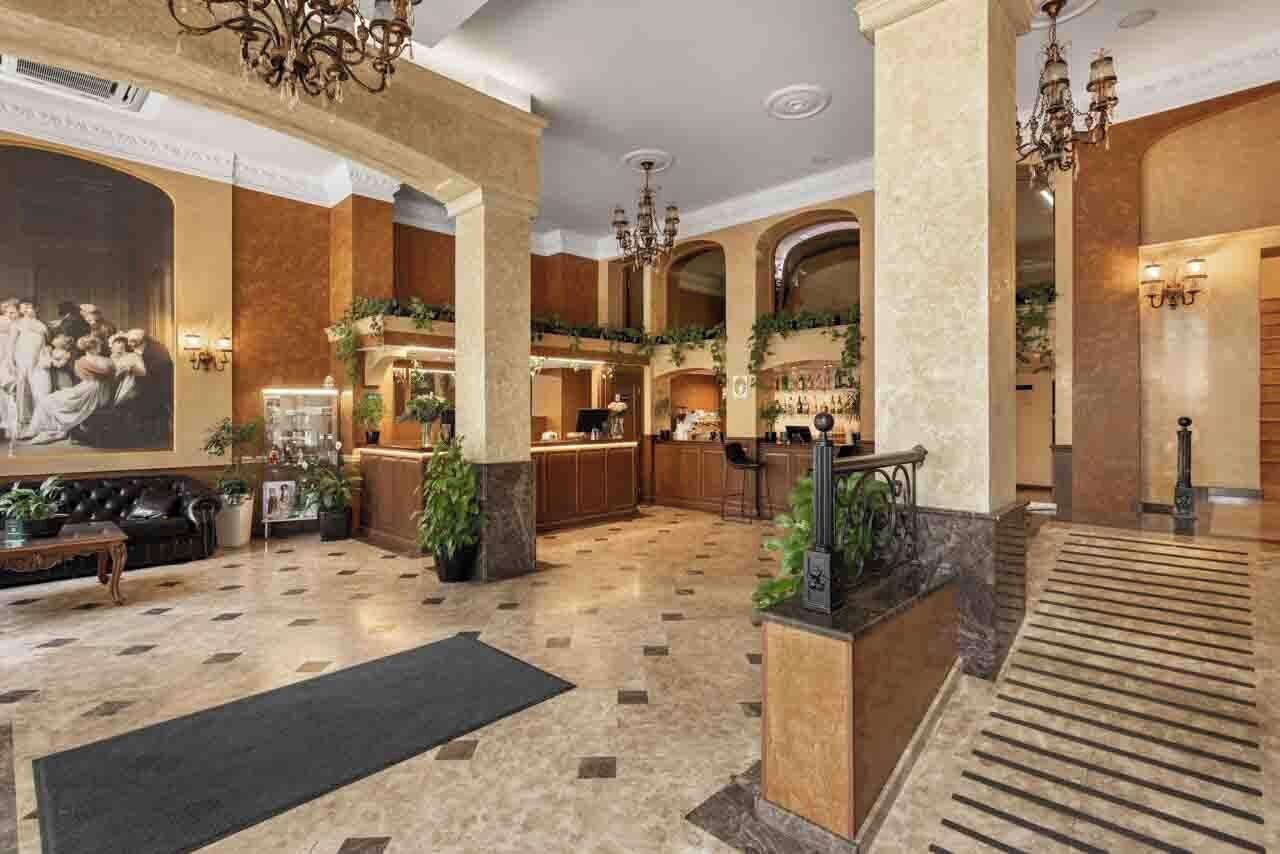 A spacious lobby with a marble floor, a reception desk, and a staircase.