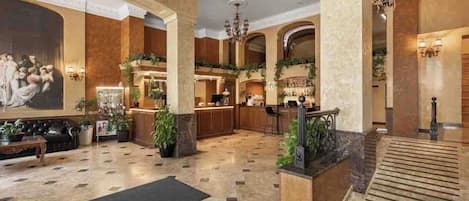 A spacious lobby with a marble floor, a reception desk, and a staircase.
