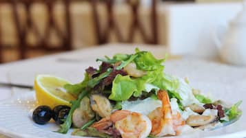 A plate of seafood salad with shrimp, olives, and lettuce.