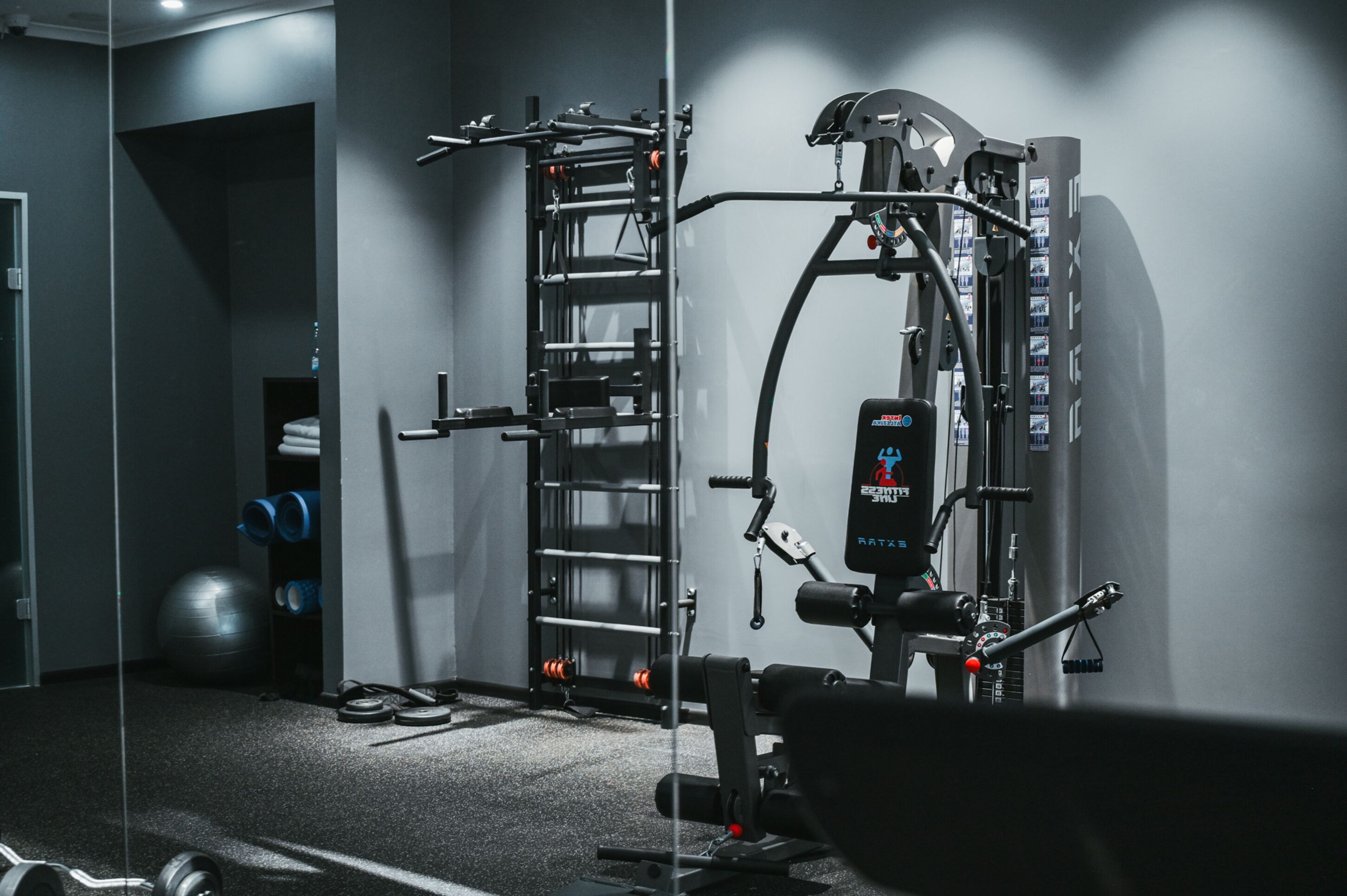 A gym with a pull-up bar, weight bench, and exercise balls.