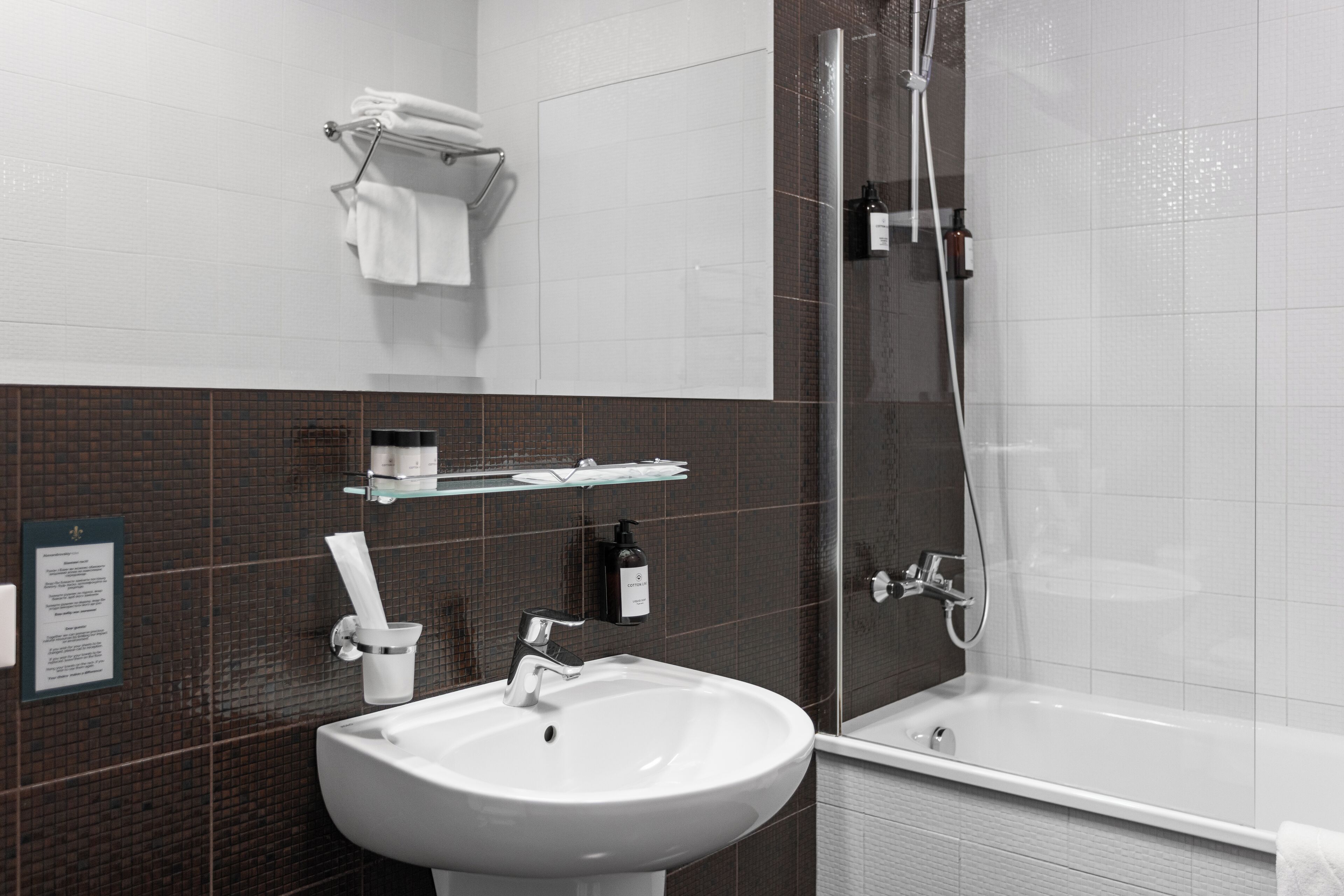 A modern bathroom with a white sink, a glass shower enclosure, and a white bathtub.