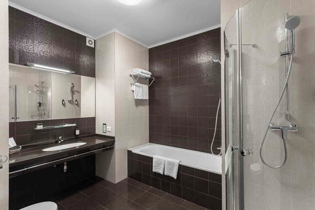 Un baño moderno con bañera, ducha, lavamanos y espejo.