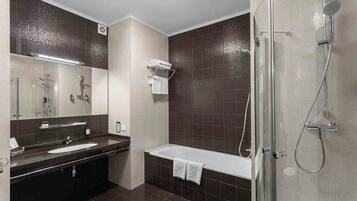 Un baño moderno con bañera, ducha, lavamanos y espejo.