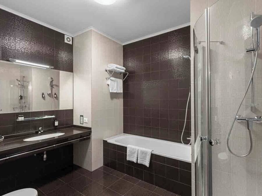 Un baño moderno con bañera, ducha, lavamanos y espejo.