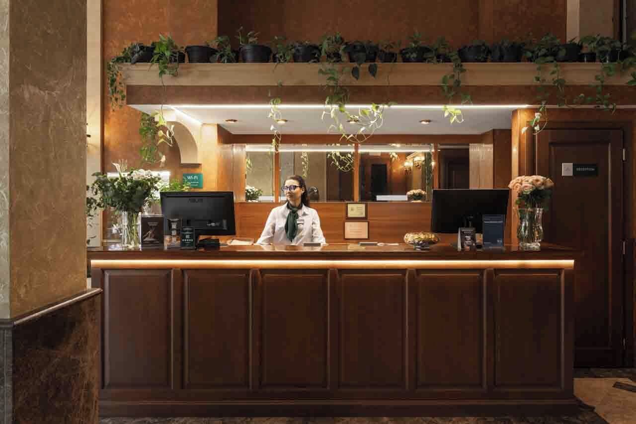 A reception desk with a receptionist, a computer, and a coffee machine.