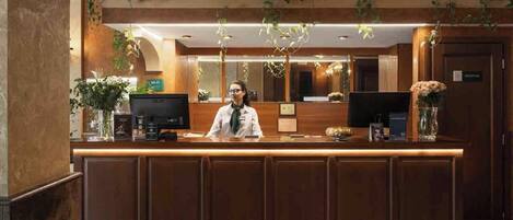 A reception desk with a receptionist, a computer, and a coffee machine.